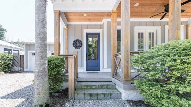 A house with a front porch, a blue door, and a wooden ceiling.