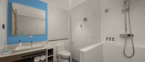 A modern bathroom with a glass-enclosed shower, a white sink, and a toilet.