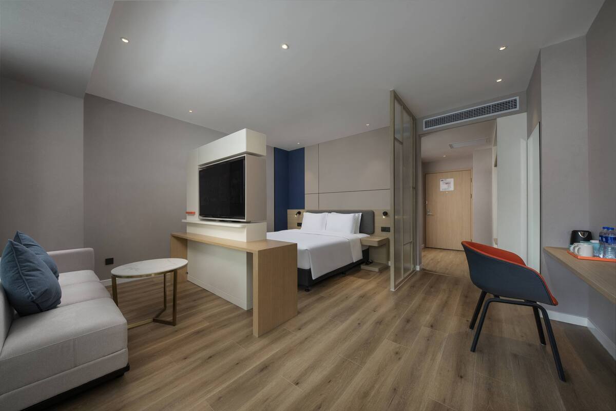 Una habitación de hotel moderna con una cama, un escritorio, una silla y un sofá.