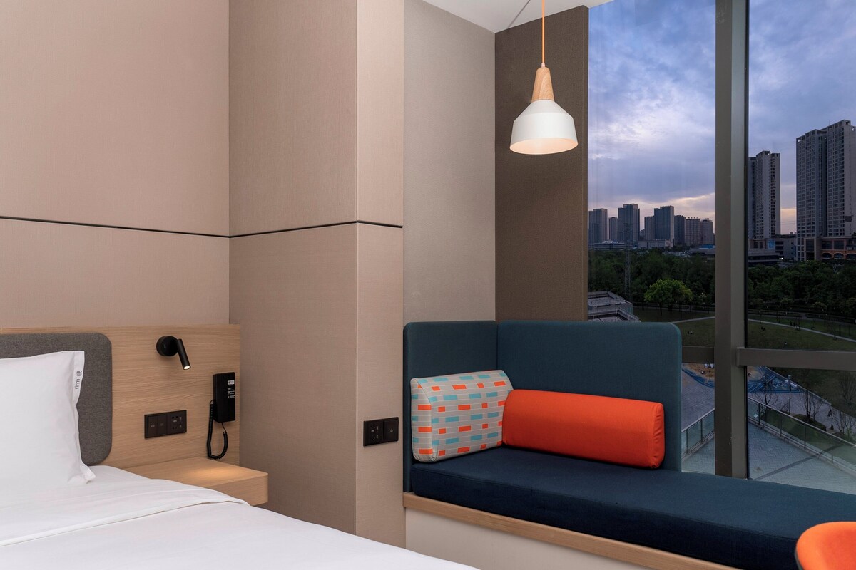 Een moderne hotelkamer met een bed, een bedtelefoon en uitzicht op de stad.