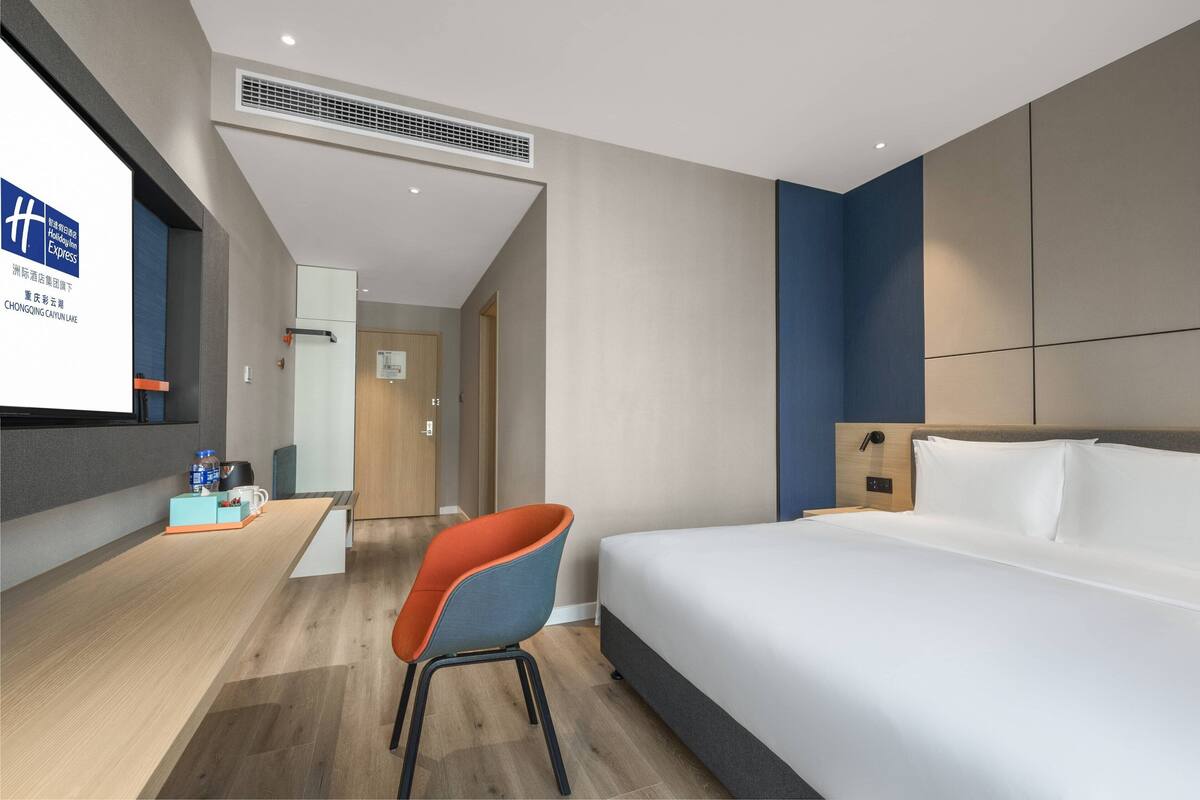 Habitación de hotel con cama, escritorio, silla y televisor mostrando un mapa.