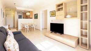 A modern living room with a flat-screen TV, a sofa, and a dining area with chairs. - Home2Book Stunning Sea Views El Porís (Porís de Abona)