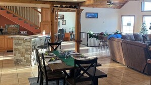 Uma sala de estar ampla com uma mesa de jantar, uma lareira e uma escada que leva a um andar superior.