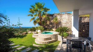 Un espacio exterior privado con un jacuzzi, escalones de piedra y una mesa con sillas.