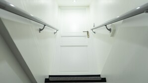 Un escalier moderne avec des rampes en verre et une porte blanche en haut.