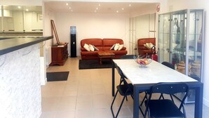 Un salon moderne comprenant un canapé, une table à manger avec des chaises et un coin cuisine équipé d’un distributeur d’eau.