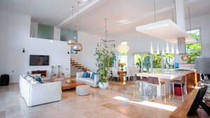 Un espacio habitable amplio con un sofá blanco, una mesa de comedor y una isla de cocina.