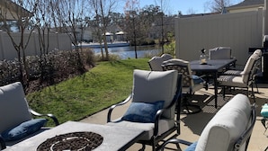 Une terrasse extérieure avec une table et des chaises, un foyer et une vue sur un lac.