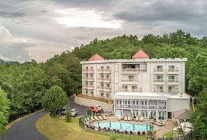 Un hôtel à plusieurs étages doté d’un espace piscine, entouré d’une végétation luxuriante.
