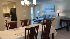 A dining area with a table set for four, a chandelier, and a kitchen in the background. - Sarasota 3 bedroom villa conveniently located on Palm Aire Golf Course community (Sarasota)