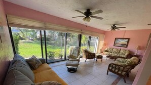 A living room with a sofa, armchairs, and a coffee table. There are large windows with a view of greenery outside. - Sarasota 3 bedroom villa conveniently located on Palm Aire Golf Course community (Sarasota)