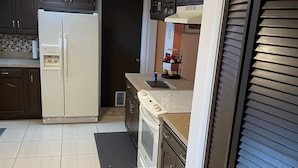 A kitchen with a refrigerator, stove, and cabinets.