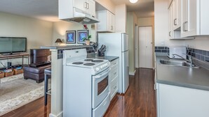 A modern kitchen with white cabinets, a stove, and a refrigerator.