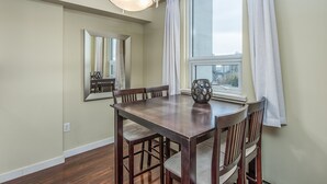 A dining area with a wooden table and chairs, a large mirror, and a window with curtains.