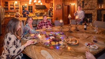 Un intérieur en bois avec une table en marbre dressée pour un repas, entourée d’invités.