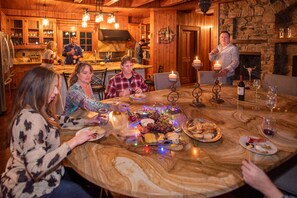 A wooden interior with a marble table set for a meal, surrounded by guests.