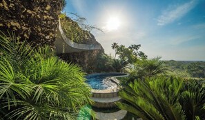 A pool surrounded by tropical vegetation and a rocky cliff. - V16b Casa la Roca  · Black Infinity Pool, Jacuzzi & Ocean View Villa (Sosua)