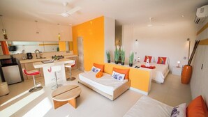 Een moderne hotelkamer met een kitchenette, een slaapbank, een eettafel en een kleine ronde tafel.