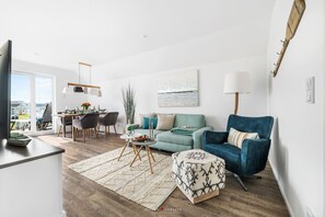A modern living room with a dining area, a sofa, a blue armchair, and a view of the outdoors. - Modern apartment with a view of the sea, a sauna, and a large balcony (Kappeln)