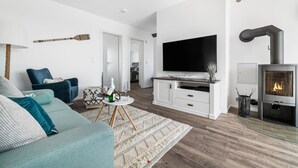 A modern living room with a sofa, TV, and fireplace. - Modern apartment with sea view, sauna and large balcony (Kappeln)