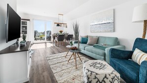 A modern living room with a sofa, a television, and a dining area with chairs and a table. - Modern apartment with sea view, sauna and large balcony (Kappeln)