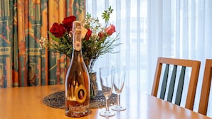 Una bottiglia di champagne, due bicchieri e un bouquet di fiori su un tavolo con una sedia.