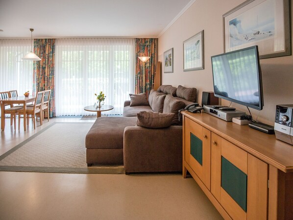 Ein modernes Wohnzimmer mit einer Couch, einem Esstisch und einem Fernseher.