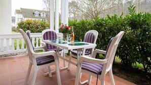 Veranda coperta con tavolo e sedie, immersa nel verde e con vista sulle case.