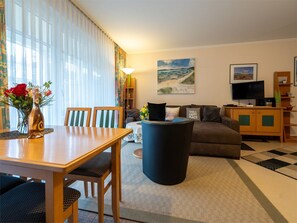 A living room with a wooden table, chairs, a sofa, a coffee table, and a television.