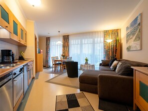 Un salon moderne comprenant un canapé, une table à manger et un coin cuisine avec une cuisinière.
