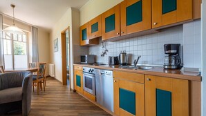 A modern kitchen with wooden cabinets, a built-in oven, microwave, and coffee maker. - Comfort apartment with 1 bedroom and terrace on the first floor (Ostseebad Binz)