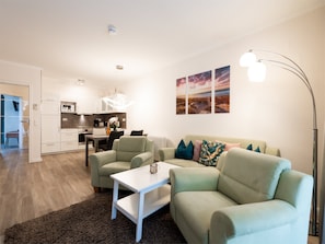 Uma sala de estar moderna com sofá, mesa de centro e um espaço de jantar com mesa e cadeiras.