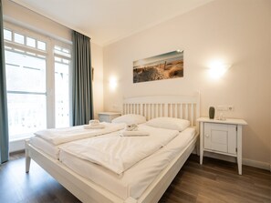 Ein Hotelzimmer mit einem großen Bett, einem Nachttisch, einer Wandlampe und einem Fenster mit Vorhängen.