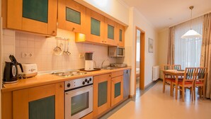 A modern kitchen with wooden cabinets, a stove, microwave, and a dining area with a table and chairs.