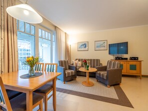 Un salon comprenant une table à manger, deux canapés, un téléviseur et un meuble.