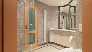 A modern bathroom with a glass shower enclosure, a white toilet, and a vanity with a mirror.