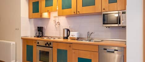 Une cuisine moderne avec des meubles en bois, un four encastré, un four à micro-ondes, une machine à café et un lave-vaisselle.