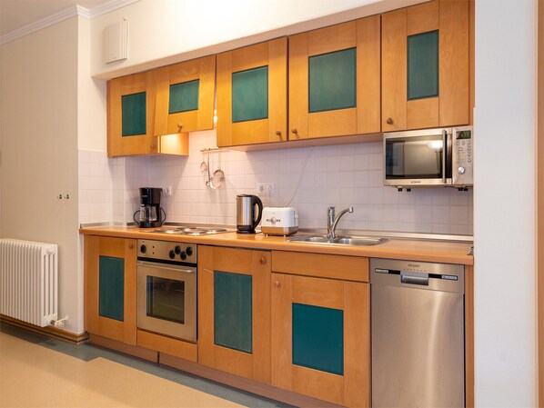 Une cuisine moderne avec des meubles en bois, un four encastré, un four à micro-ondes, une machine à café et un lave-vaisselle.