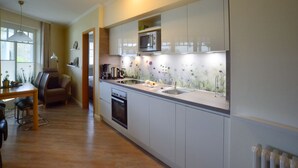 Una cucina moderna con mobili bianchi, un forno a microonde e un lavello. C'è un'area pranzo con tavolo e sedie.