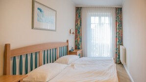 En pænt redt seng med sengegavl i træ, et natbord og et natbord med lampe.