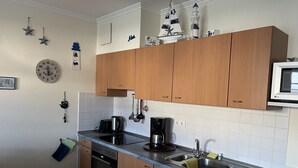 A modern kitchen with wooden cabinets, a stainless steel sink, a built-in oven, and a microwave. - Comfort apartment with 1 bedroom and terrace on the first floor (Ostseebad Binz)