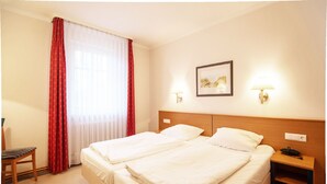 A hotel room with two beds, a chair, a nightstand, a lamp, and a painting on the wall. - Classic apartment with 1 bedroom and balcony on the upper floor (Ostseebad Binz)