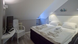 A bedroom with a bed, a desk, a chair, and a small wall-mounted shelf. - Comfort plus apartment with 1 bedroom and balcony on the top floor (Ostseebad Binz)