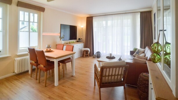 Una sala de estar moderna con comedor, piso de madera y ventanas grandes.