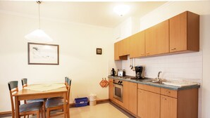 A compact kitchen with wooden cabinets, a dining table with chairs, a coffee maker, and a toaster. - Komfort Ferienwohnung mit 1 Schlafzimmer und Balkon im Obergeschoss (Ostseebad Binz)