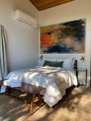 Cozy retreat with a large bed, bedside tables, and a modern art piece above.