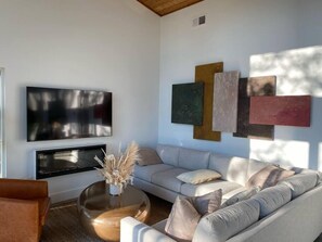 Relax in this stylish living room with a large flat-screen TV, comfortable sofa, and round coffee table.