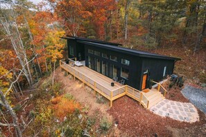 Escape to a serene retreat nestled in the forest, with a spacious deck and expansive views of the surrounding woodland.