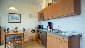 Una cocina compacta con armarios de madera, horno integrado y cafetera.