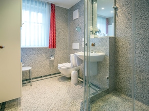 A bathroom with a glass shower enclosure, a white sink, and a toilet.